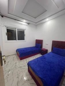 Habitación con 2 camas y sábanas azules. en blue city apartment 1, en Chefchaouen