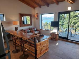 sala de estar con mesa, sofá y ventanas en Tres Vistas en San Carlos de Bariloche