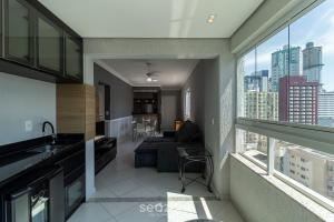 a kitchen and living room with a view of a city at Apto c/ varanda 600m da orla Centro BC EJF0702 in Balneário Camboriú