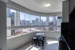 a balcony with a table and stools in front of a window at Apto c/ varanda 600m da orla Centro BC EJF0702 in Balneário Camboriú