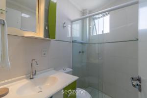 a bathroom with a sink and a glass shower at Apto c/ varanda 600m da orla Centro BC EJF0702 in Balneário Camboriú +25 photos