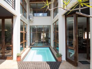 an indoor swimming pool in a house with glass walls at Jopasso Guest House in Pretoria