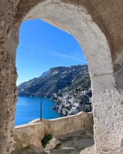 - une vue sur l'océan depuis une fenêtre en pierre dans l'établissement Mela & Cannella accommodation, à Minori