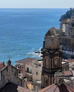 a clock tower on top of a building next to the ocean at Mela & Cannella accommodation in Minori
