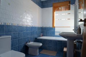 a blue tiled bathroom with a toilet and a sink at Namawa Surfhouse in Chiclana de la Frontera