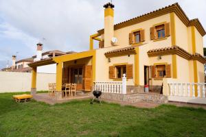 a yellow house with a table and chairs in the yard at Namawa Surfhouse in Chiclana de la Frontera