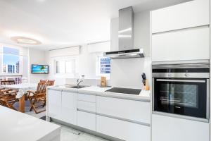 eine Küche mit weißen Schränken und einem Herd mit Backofen in der Unterkunft Gemelos 28-16D Deluxe Apartment Levante Beach in Benidorm