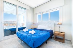 ein Schlafzimmer mit einem blauen Bett und großen Fenstern in der Unterkunft Gemelos 28-16D Deluxe Apartment Levante Beach in Benidorm + 31 Fotos