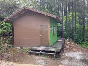 um pequeno barracão com um alpendre de madeira na floresta em Iiji Tent Mura - Camp - Vacation STAY 76594v em Ena