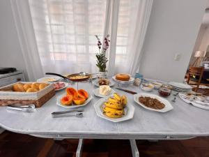 einen Tisch mit Teller mit Lebensmitteln und Obst in der Unterkunft Residencia Dago Suítes in Campos do Jordão
