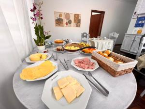 einen Tisch mit Käse und anderen Lebensmitteln darauf in der Unterkunft Residencia Dago Suítes in Campos do Jordão