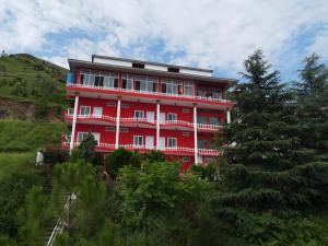 a red building on a hill with trees in front at RED ROSE HOTEL & RESORT Mansehra in Mānsehra