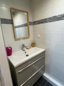 a white bathroom with a sink and a mirror at Charmant appartement in Béguey