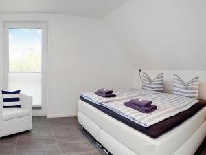a white bedroom with a bed and a white chair at Ferienhaus am Yachthafen in Peenemuende in Peenemünde