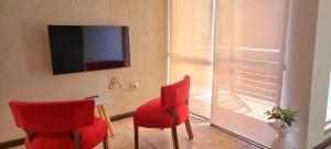 sala de estar con 2 sillas rojas y TV en Apex Apart en Mendoza