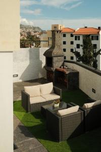 un patio con 2 sofás y una chimenea en el balcón en CASA15 Guesthouse Funchal en Funchal