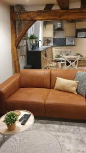 un sofá marrón en una sala de estar con cocina en Petite bulle de Saint Remacle, en Stavelot