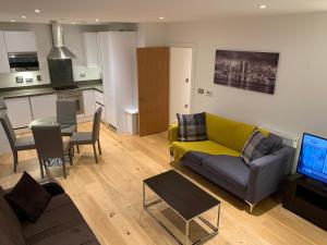 a living room with a yellow couch and a kitchen at Dockland Excel 2 Bedroom Apartment in London
