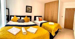 a bedroom with two beds with yellow sheets at Dockland Excel 2 Bedroom Apartment in London