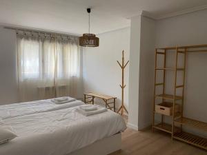 Dormitorio blanco con cama y estante en La Casina de Rodiles, en Liñero
