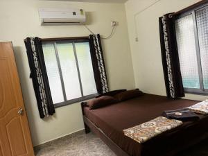 1 dormitorio con 1 cama y ventana con aire acondicionado en Royal Devbaug Holiday Home, en Malvan