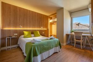 1 dormitorio con cama con almohadas verdes y escritorio en Apartamento Alminar, en Granada