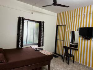 a room with a bed and a desk and a window at Royal Devbaug Holiday Home in Malvan