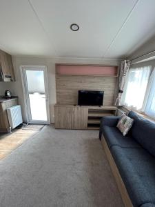 a living room with a couch and a flat screen tv at Beautiful Caravan With Decking At Trevella Holiday Park, Newquay, Ref 98082hs in Newquay