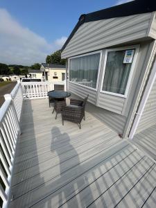 a deck with two benches and a table on a house at Beautiful Caravan With Decking At Trevella Holiday Park, Newquay, Ref 98082hs in Newquay