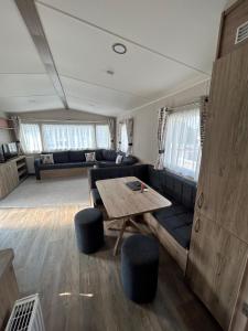 a living room with a couch and a table at Beautiful Caravan With Decking At Trevella Holiday Park, Newquay, Ref 98082hs in Newquay