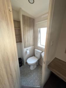 a small bathroom with a toilet and a window at Beautiful Caravan With Decking At Trevella Holiday Park, Newquay, Ref 98082hs in Newquay