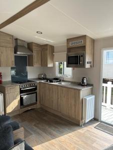 a kitchen with wooden cabinets and a stove top oven at Beautiful Caravan With Decking At Trevella Holiday Park, Newquay, Ref 98082hs in Newquay