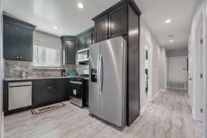a kitchen with a stainless steel refrigerator and black cabinets at ৎ୭ LA Breeze Home ৎ୭ in Los Angeles