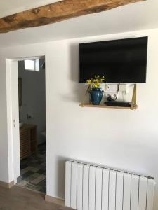 a flat screen tv on a wall with a radiator at Maison de campagne : « Après moi » / Baie de Somme in Lanchères