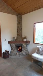 a living room with a stone fireplace in a house at Pousada Vilarejo das Oliveiras in Queimada