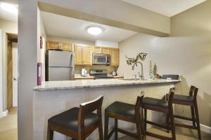 a kitchen with a counter with chairs and a refrigerator at Tannhauser 225 in Breckenridge