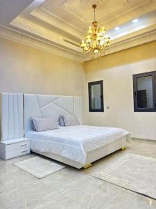 una camera da letto con un grande letto bianco e un lampadario a braccio di Villa Artemis (Ground Floor) a Rejiche