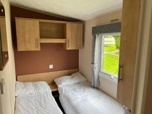 two beds in a small room with a window at Lovely Caravan At Lower Hyde Holiday Park, Isle Of Wight Ref 24001g in Shanklin