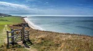 a fence on the side of a hill overlooking the ocean at Lovely Caravan At Lower Hyde Holiday Park, Isle Of Wight Ref 24001g in Shanklin