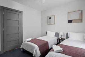 a white room with two beds and a door at Modern Architect's Duplex by CozySuites in Indianapolis