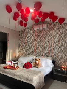 misia siedzącego na łóżku z czerwonymi balonami w obiekcie HOTEL CAMPESTRE Palma w mieście Villavicencio