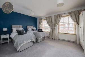 two beds in a bedroom with blue walls and windows at Leeward House - Luxury, Spacious, Sea View Apartment, Parking, Central Lymington in Lymington