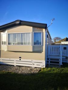 a small yellow trailer with a fence in a yard at Lovely Caravan With Decking At Solent Breeze In Hampshire Ref 38195sb in Warsash