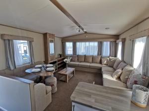 sala de estar con sofá y mesa en Lovely Caravan With Decking At Solent Breeze In Hampshire Ref 38195sb en Warsash