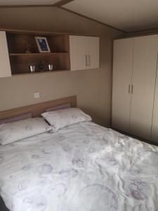 a bedroom with a large bed with two pillows at Lovely Caravan With Decking At Solent Breeze In Hampshire Ref 38195sb in Warsash
