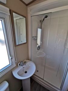 La salle de bains est pourvue d'un lavabo et d'une douche. dans l'établissement Lovely Caravan With Decking At Solent Breeze In Hampshire Ref 38195sb, à Warsash