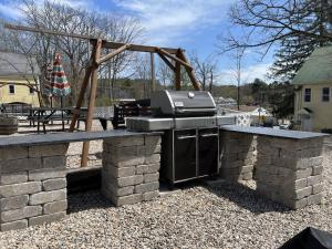 een barbecue op een stenen patio met een speeltuin bij Main House - 3 Story 5 Bed/ 3 Bath - Wolfeboro in Wolfeboro