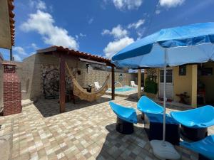 une terrasse avec des chaises bleues et un parasol dans l'établissement Casa Dona Van Van Praia do Francês, à Marechal Deodoro