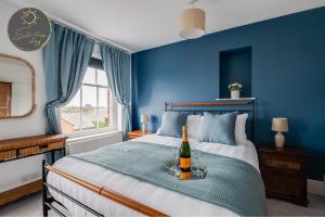 um quarto azul com uma garrafa de vinho numa cama em Leeward House - Luxury, Spacious, Sea View Apartment, Parking, Central Lymington em Lymington