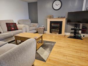 a living room with couches and a fireplace with a clock at ALLARDYCE in Kincardine